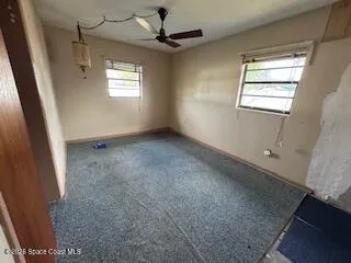 en empty room with windows and ceiling fan