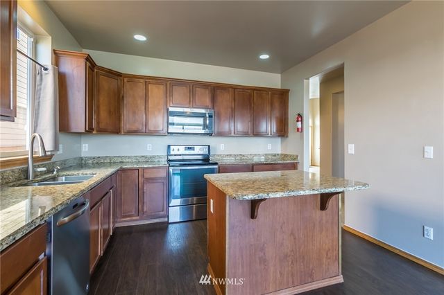 a kitchen with stainless steel appliances granite countertop a stove a sink and a microwave