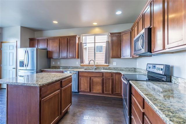 a kitchen with stainless steel appliances granite countertop a refrigerator a sink a stove and cabinets