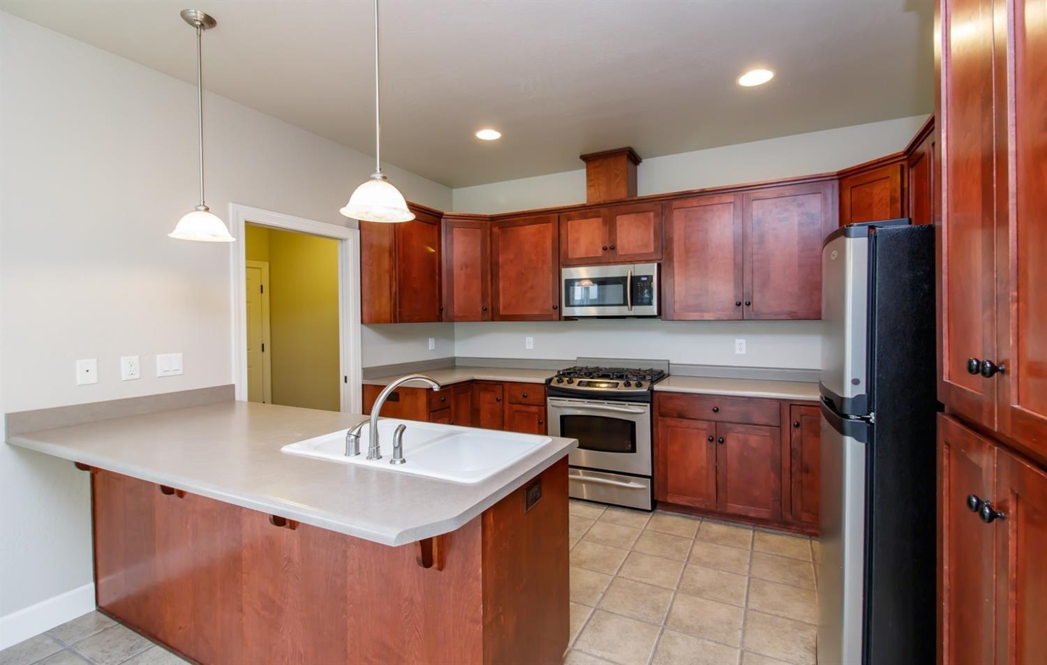 1135 Rustler Peak Street Central Point, OR 97502 - Photo 6 of 17 a kitchen with stainless steel appliances granite countertop a sink a stove and a refrigerator