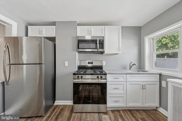 a kitchen with cabinets stainless steel appliances and wooden floor