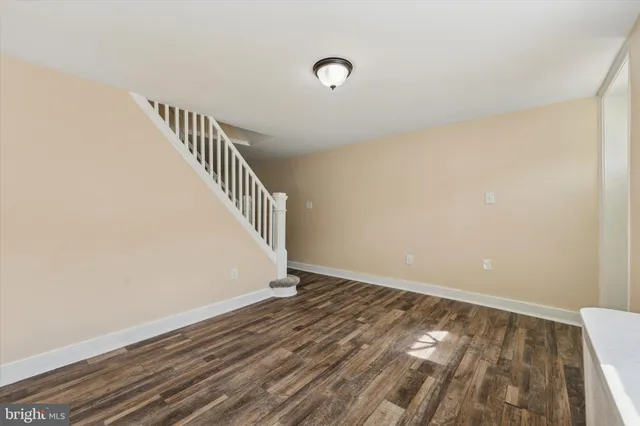 a view of an empty room with wooden floor and stairs