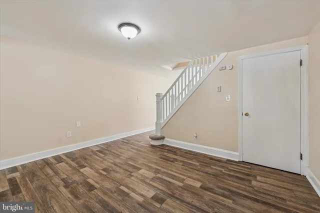 a view of an empty room with wooden floor and stairs