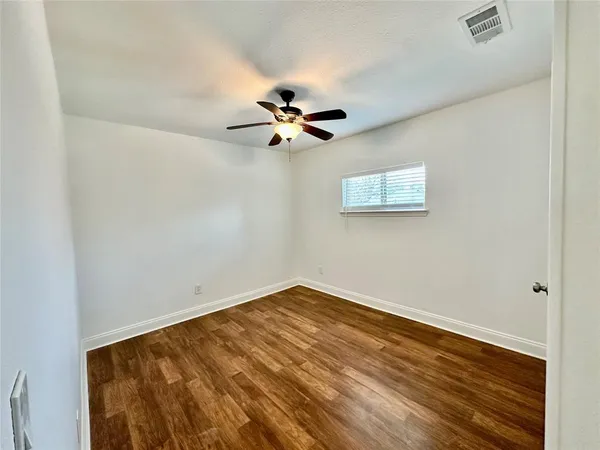 an empty room with a window and a ceiling fan