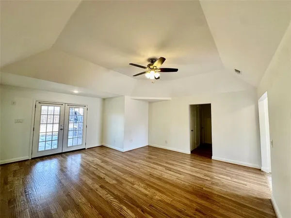 a view of an empty room with window and wooden floor