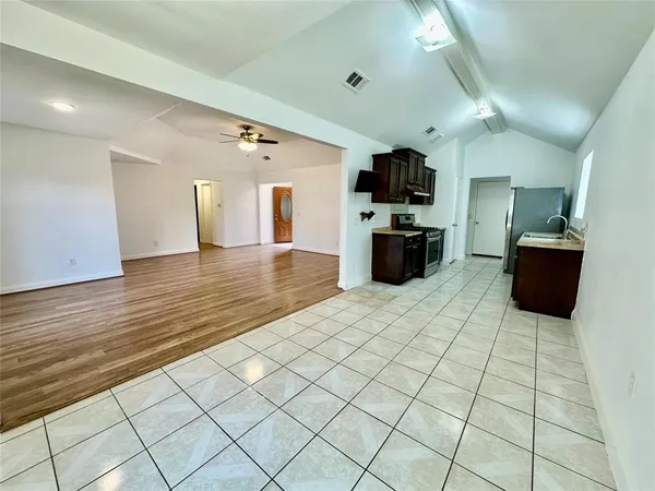 a living room with stainless steel appliances kitchen island granite countertop a sink and cabinets