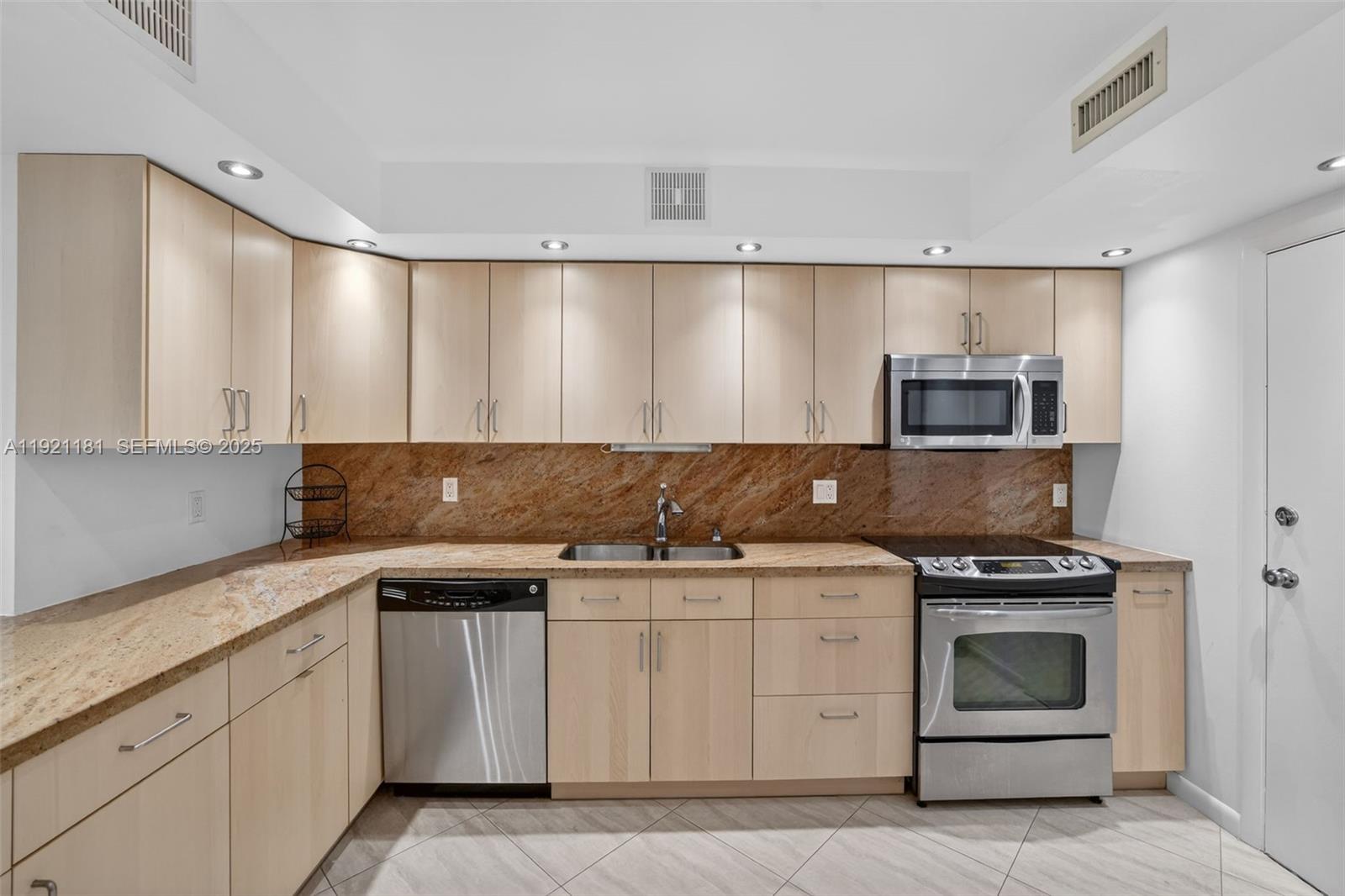 200 Diplomat Parkway, Unit 531 Hallandale Beach, FL 33009 - Photo 12 of 45 a kitchen with granite countertop white cabinets and stainless steel appliances