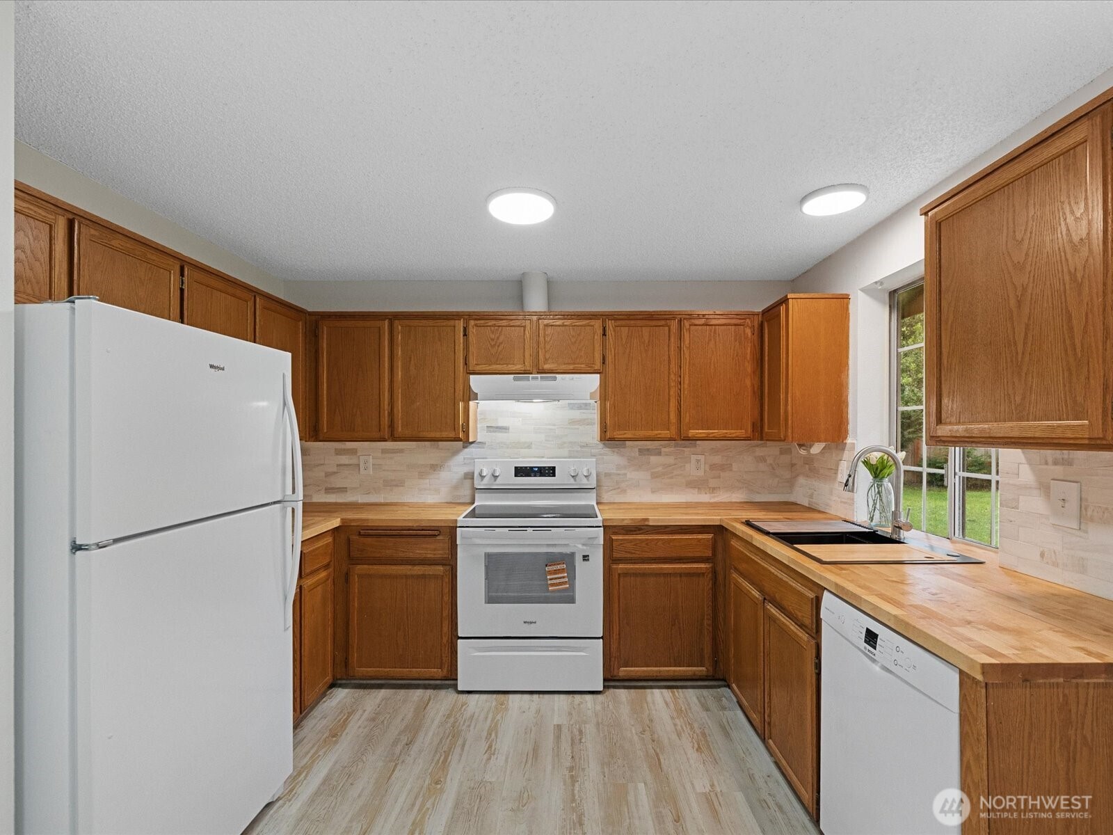 7822 Songbird Way Clinton, WA 98236 - Photo 9 of 28 a kitchen with a sink a refrigerator and wooden floor
