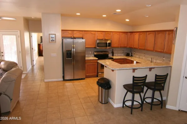 a kitchen with stainless steel appliances kitchen island granite countertop a sink and a refrigerator