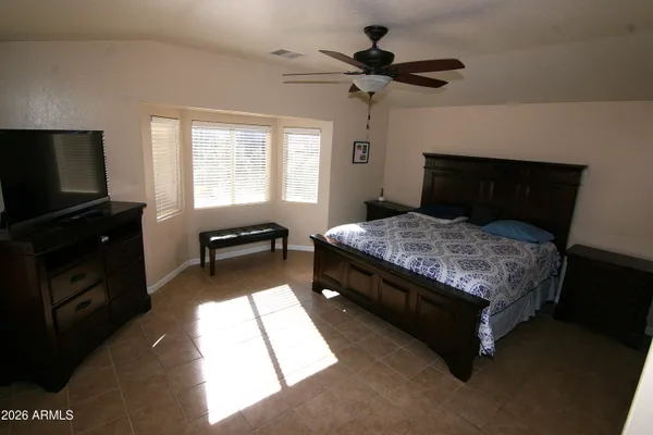 a bedroom with a bed and a flat tv screen on the dresser
