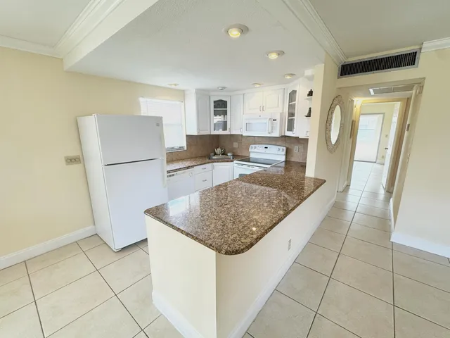 a kitchen with stainless steel appliances granite countertop a refrigerator a sink and a counter