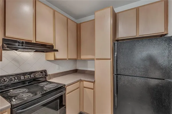 a kitchen with stainless steel appliances granite countertop a refrigerator a stove and a sink with wooden cabinets