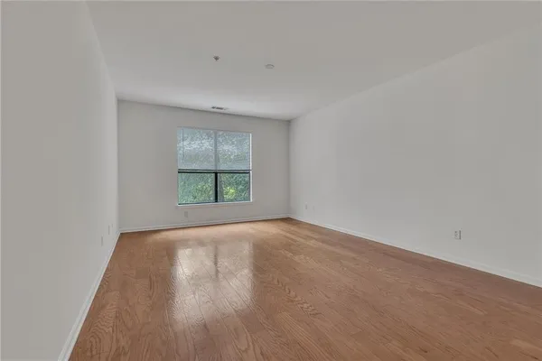 an empty room with wooden floor and windows