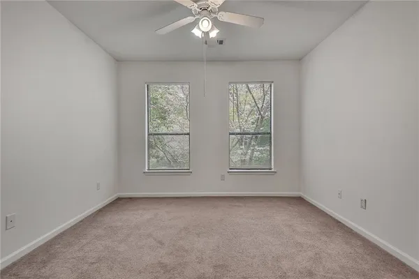 an empty room with a ceiling fan and closet area