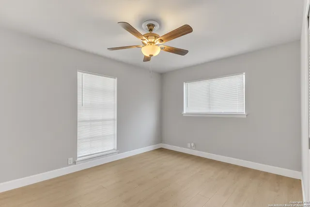 an empty room with window and ceiling fan