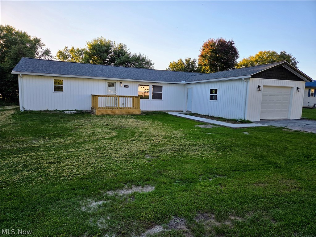 6145 Virginia Road Nashport, OH 43830 - Photo 1 of 24 Single-story residence featuring white vertical siding, a wood-finish front deck, an attached garage with a white overhead door, and a concrete pathway leading to the garage
