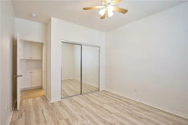 an empty room with wooden floor ceiling fan and windows