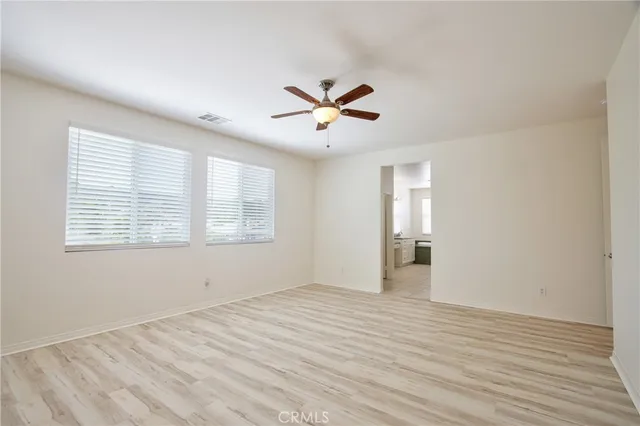 an empty room with wooden floor fan and windows