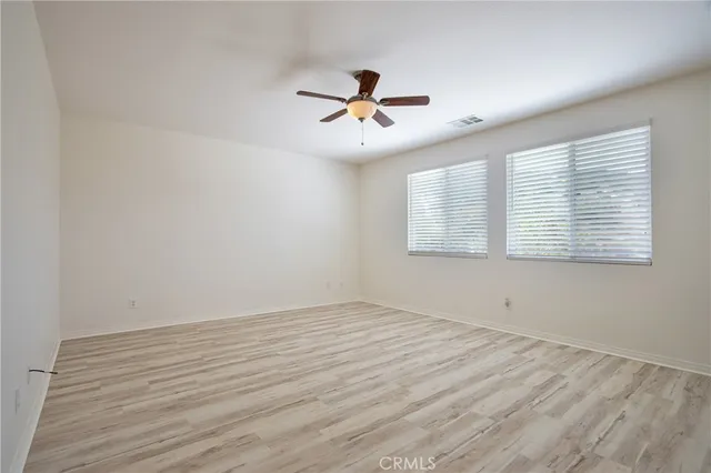 an empty room with wooden floor ceiling fan and window