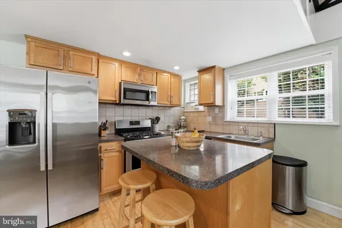 a kitchen with stainless steel appliances granite countertop a stove a sink dishwasher and a refrigerator with wooden cabinets