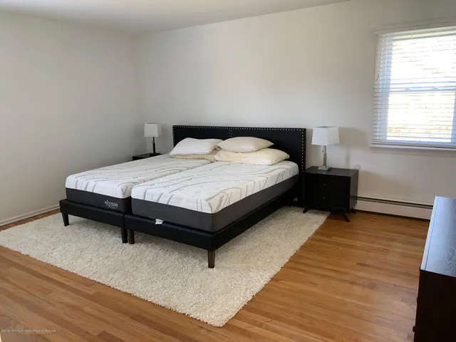 a spacious bedroom with a bed and wooden floor