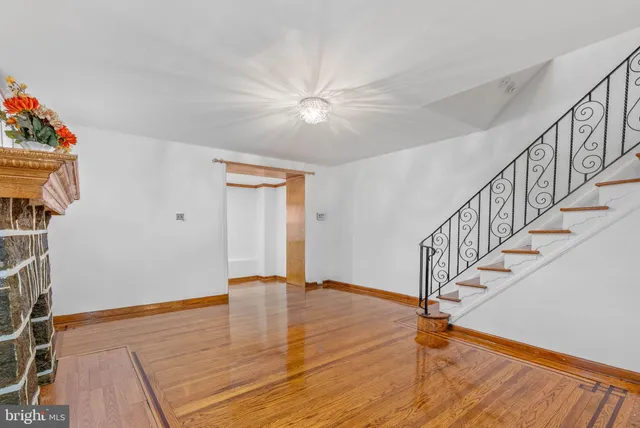 a view of an empty room with wooden floor and a chandelier