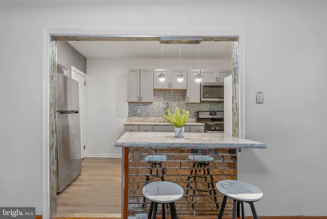 a kitchen with stainless steel appliances a table and chairs in it