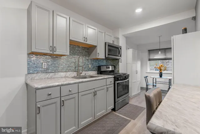 a kitchen with stainless steel appliances granite countertop a sink stove refrigerator and cabinets