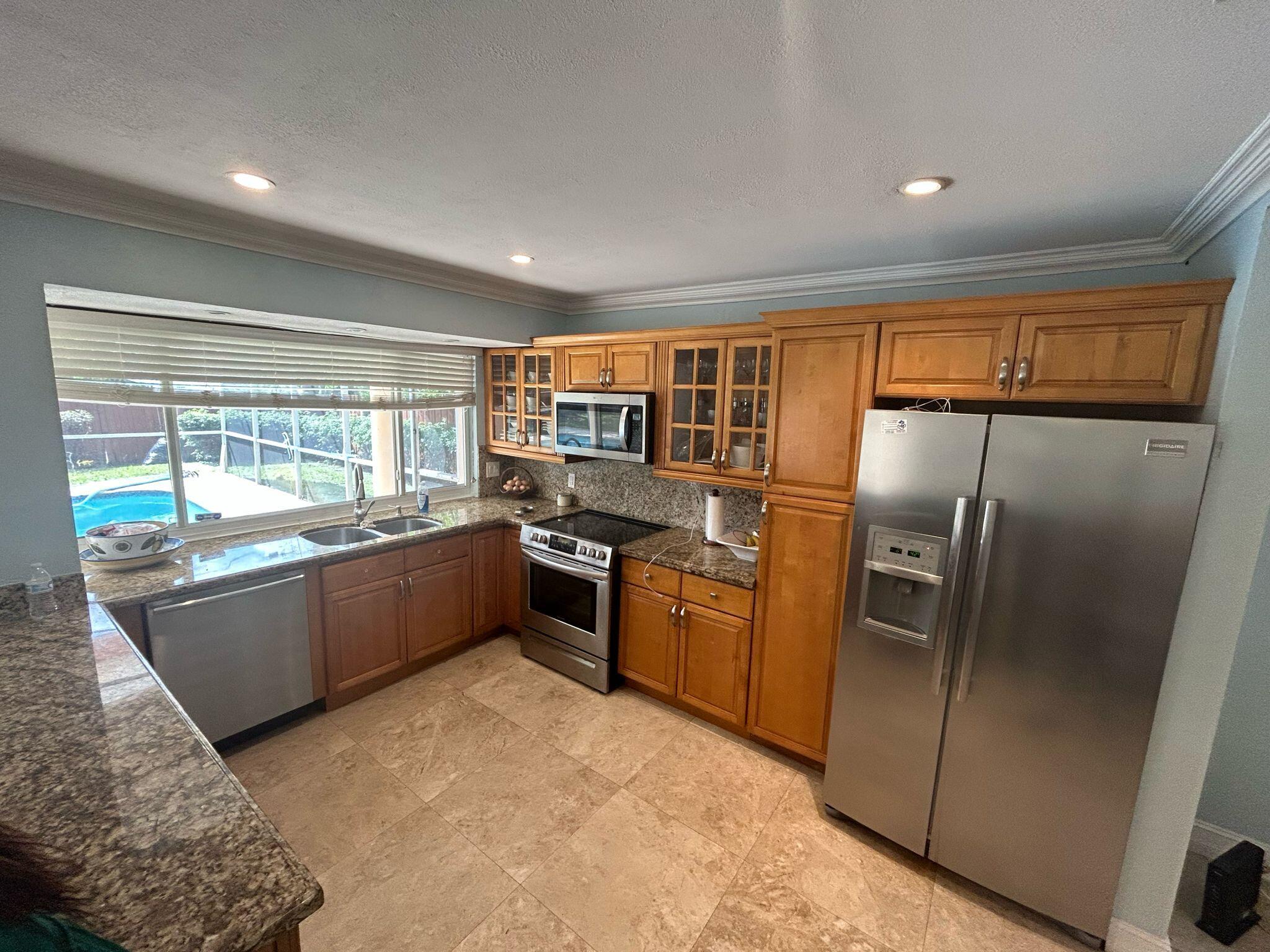 5200 Adams Street Hollywood, FL 33021 - Photo 5 of 24 a kitchen with granite countertop a refrigerator and wooden cabinets