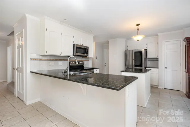 a kitchen with stainless steel appliances granite countertop a sink a microwave a refrigerator and a granite counter tops