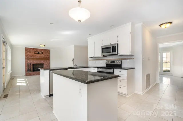 a kitchen with granite countertop a sink a counter top space appliances and cabinets