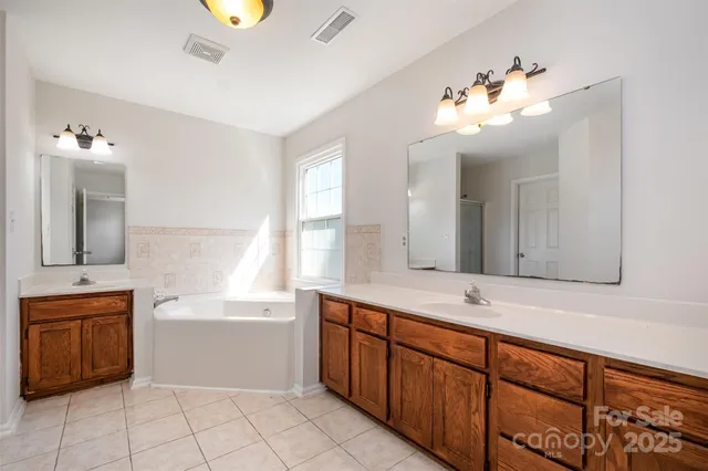 a spacious bathroom with a double vanity sink a mirror a bathtub and a window