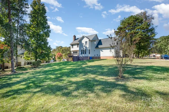 a view of a house with a big yard and large trees