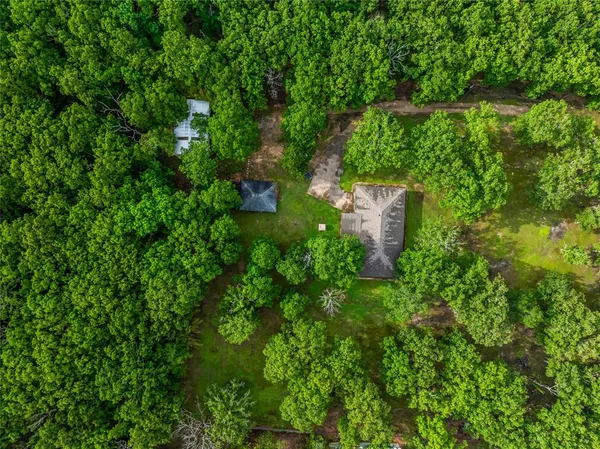 an aerial view of residential house with outdoor space and trees all around