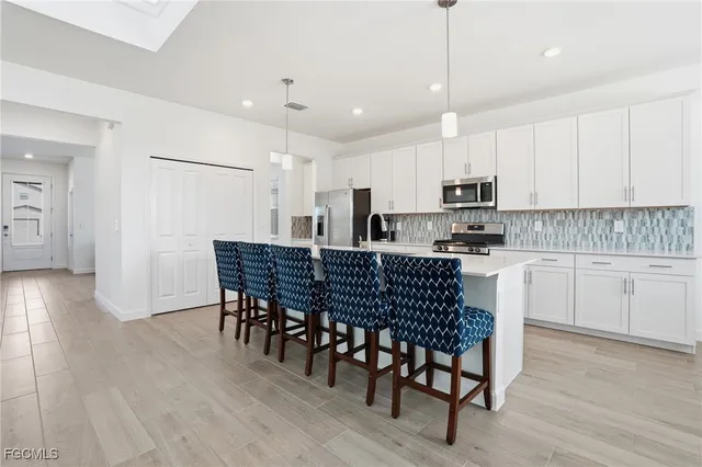 a kitchen with stainless steel appliances granite countertop a white table and chairs