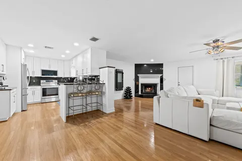 a living room with stainless steel appliances kitchen island wooden floors and white cabinets