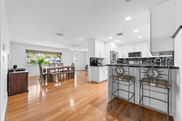 a kitchen with stainless steel appliances granite countertop wooden cabinets a stove a sink a dining table and chairs