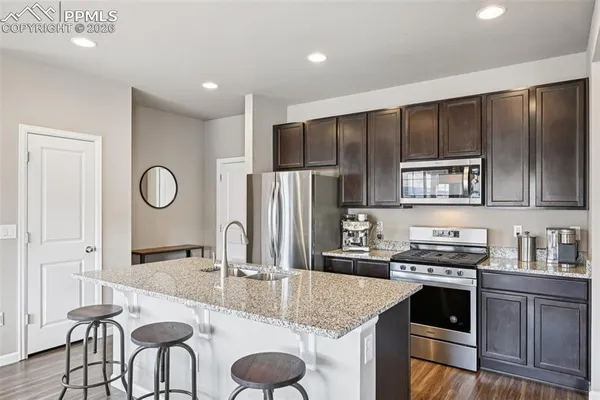 a open kitchen with granite countertop a dining table chairs and wooden floor