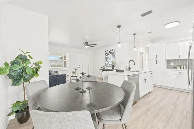 a dining room with furniture a potted plant and kitchen view