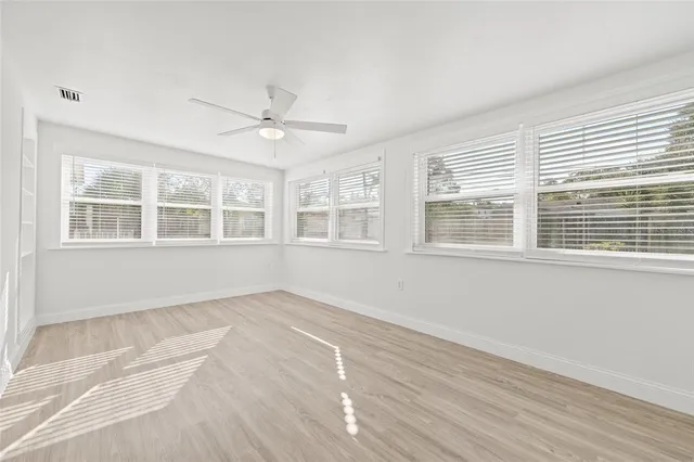a view of an empty room with a window and wooden floor