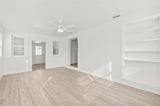 a view of an empty room with window and wooden floor