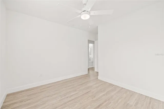 an empty room with wooden floor and fan