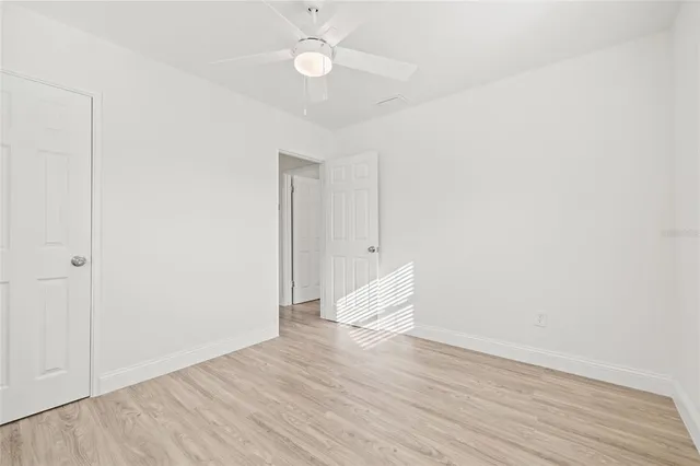 an empty room with wooden floor and fan
