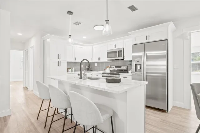 a kitchen with stainless steel appliances granite countertop a refrigerator a sink a stove a dining table and chairs