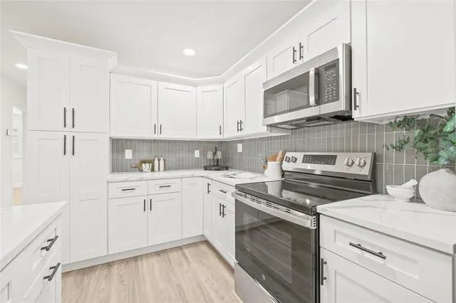 a kitchen with cabinets stainless steel appliances and wooden floor
