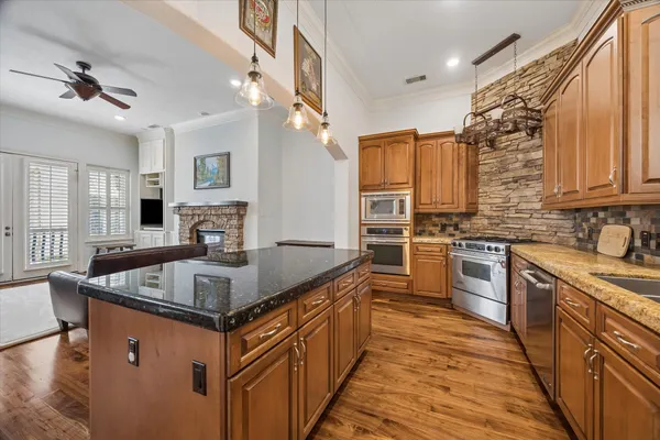 a kitchen with stainless steel appliances granite countertop a sink a stove top oven a counter space and cabinets
