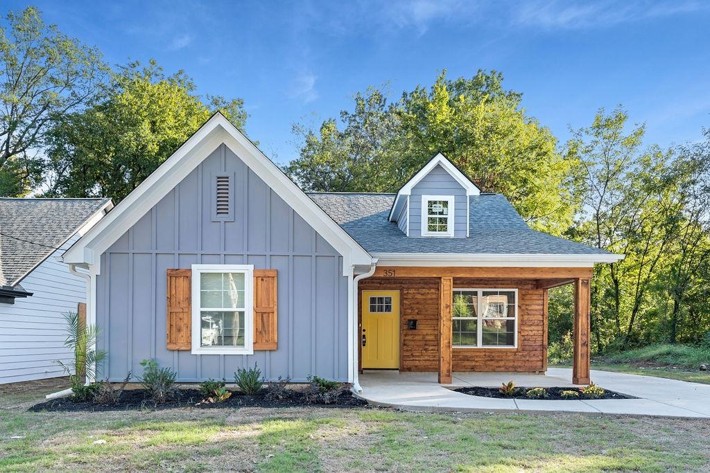 View of front of house featuring roof with shingles, a porch, board and batten siding, and a front lawn