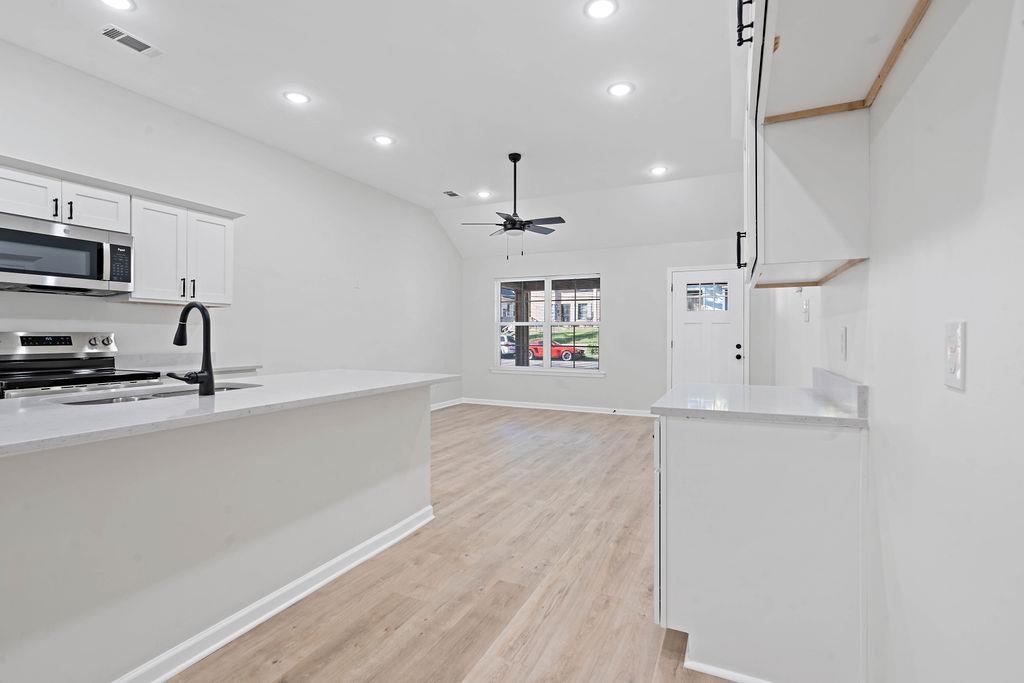 351 Edith Avenue Memphis, TN 38126 - Photo 7 of 15 Kitchen with white cabinetry, appliances with stainless steel finishes, vaulted ceiling, recessed lighting, and light stone counters