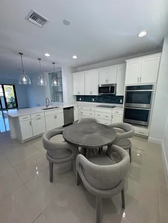 a kitchen with stainless steel appliances granite countertop a sink a stove a microwave a center island and chairs