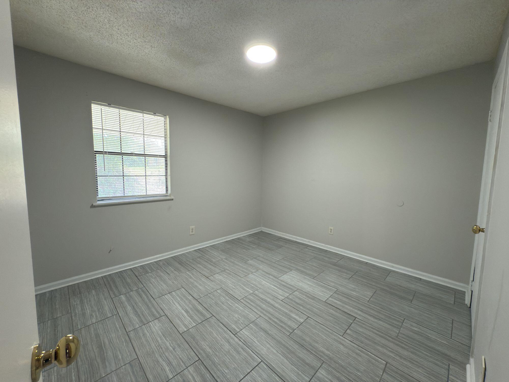 4260 Highway 90, Unit 43 Pace, FL 32571 - Photo 4 of 6 an empty room with wooden floor and windows